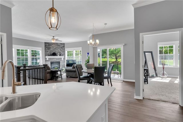 11961 S Tallgrass Dr Unit 403, Olathe, KS 66061 - kitchen featuring a ceiling fan, a sink, a stone fireplace, ornamental molding, and hanging light fixtures