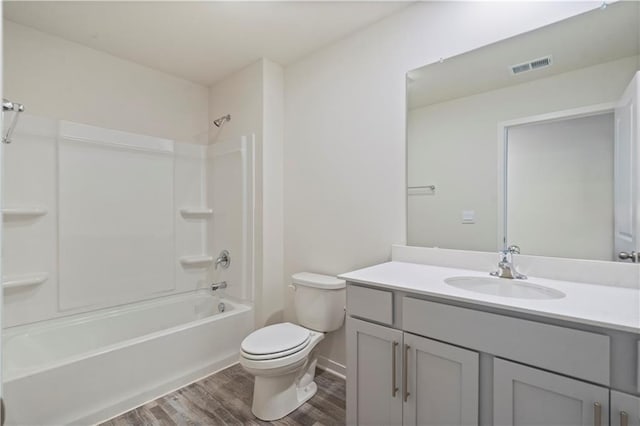 full bathroom with wood finished floors, toilet, vanity, shower / tub combination, and baseboards