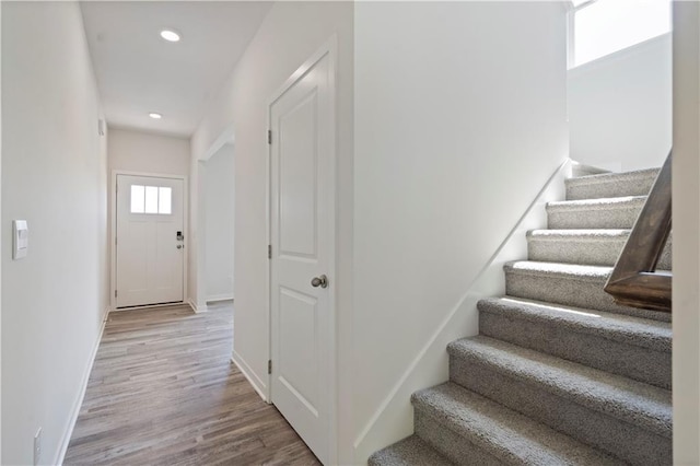 staircase featuring wood finished floors, baseboards, and recessed lighting