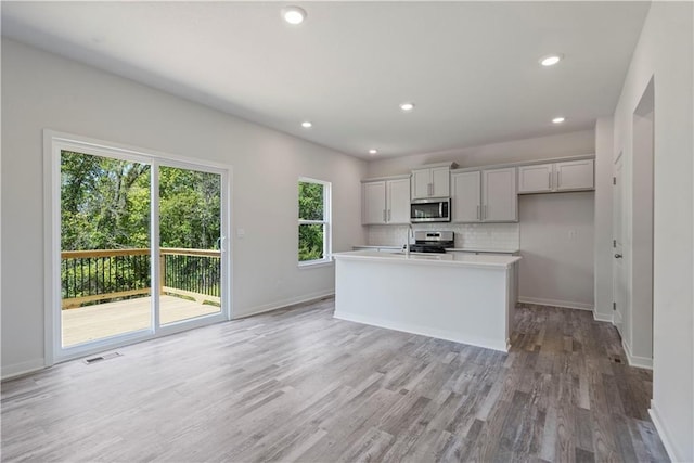 kitchen with appliances with stainless steel finishes, light wood-type flooring, tasteful backsplash, baseboards, and recessed lighting