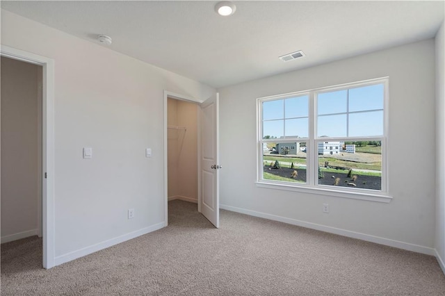 unfurnished bedroom featuring carpet flooring, a spacious closet, baseboards, and a closet