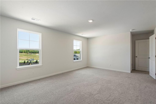 spare room featuring light carpet and baseboards