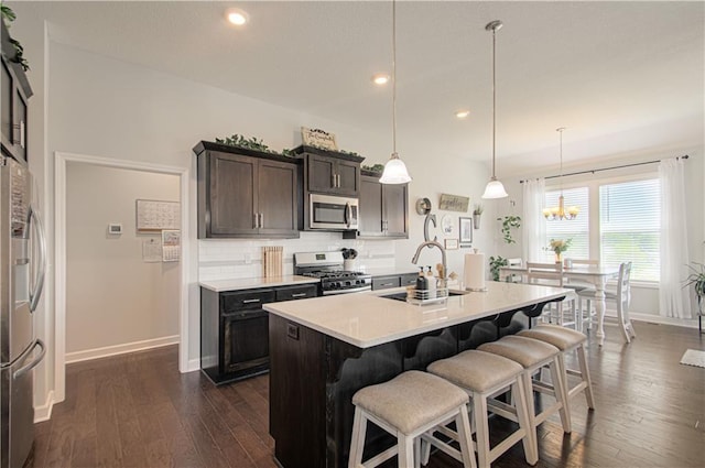 11021 N Oxford Ave, Kansas City, MO 64157 - kitchen with appliances with stainless steel finishes, baseboards, a sink, a breakfast bar area, and dark wood finished floors