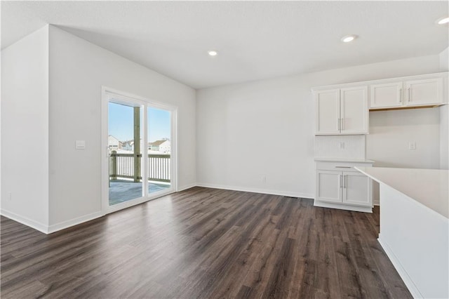 unfurnished dining area with dark wood-type flooring, baseboards, and recessed lighting