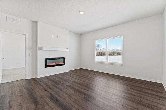 unfurnished living room with dark wood-style floors, a glass covered fireplace, and baseboards