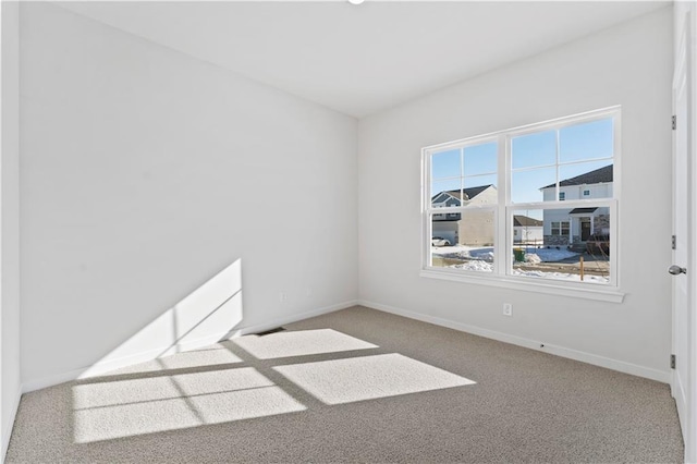 spare room featuring carpet floors and baseboards