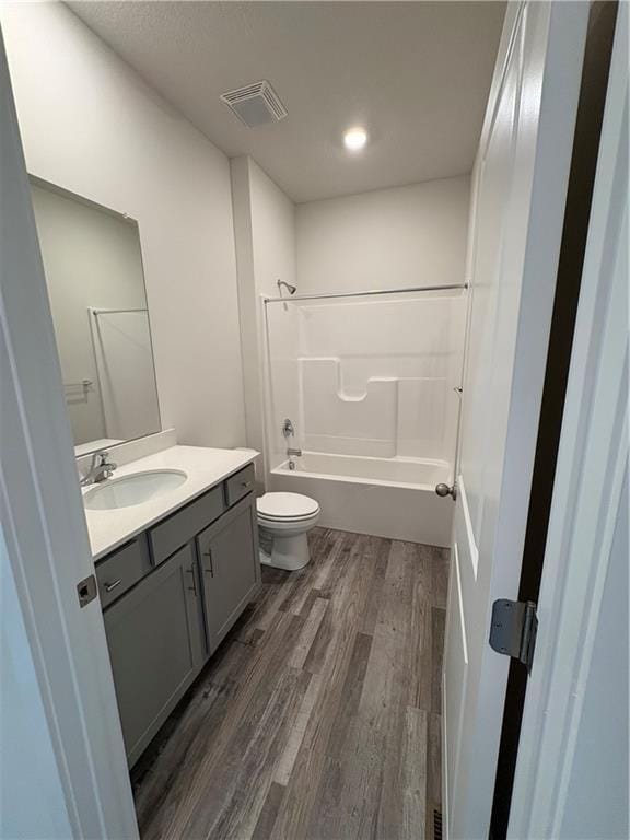 full bath featuring wood finished floors, toilet, vanity, and shower / bathtub combination