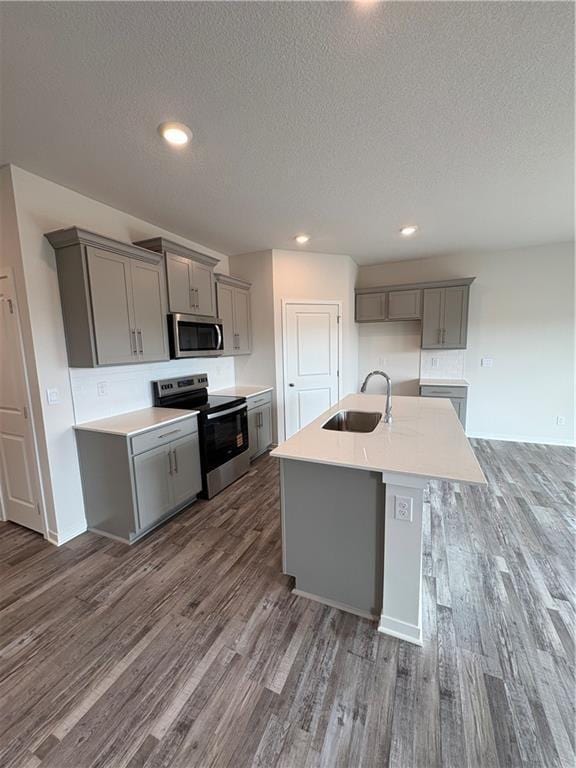 kitchen featuring appliances with stainless steel finishes, gray cabinetry, a sink, dark wood-style floors, and a textured ceiling