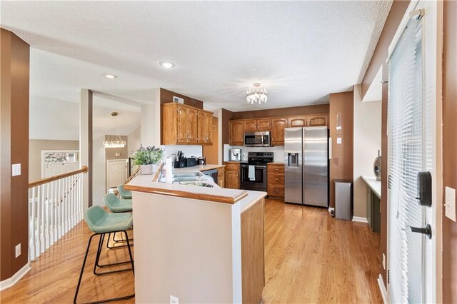 7703 NE 74th Ter, Kansas City, MO 64158 - kitchen featuring appliances with stainless steel finishes, a chandelier, brown cabinetry, light wood-type flooring, and recessed lighting