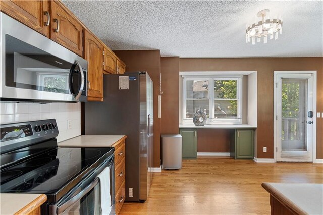 7703 NE 74th Ter, Kansas City, MO 64158 - kitchen featuring stainless steel appliances, light wood-style floors, light countertops, and a textured ceiling