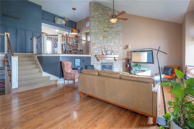 10111 N Tullis Dr, Kansas City, MO 64157 - living area featuring wood finished floors, a ceiling fan, stairway, a stone fireplace, and high vaulted ceiling