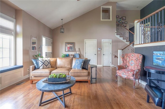 10111 N Tullis Dr, Kansas City, MO 64157 - living area with wood finished floors, high vaulted ceiling, stairs, and baseboards