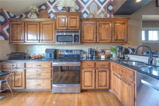 10111 N Tullis Dr, Kansas City, MO 64157 - kitchen with stainless steel appliances, a sink, brown cabinetry, light wood-type flooring, and lofted ceiling
