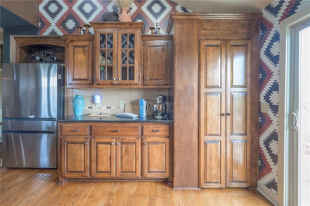 10111 N Tullis Dr, Kansas City, MO 64157 - kitchen featuring freestanding refrigerator, brown cabinetry, dark countertops, light wood finished floors, and wallpapered walls