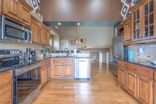 10111 N Tullis Dr, Kansas City, MO 64157 - kitchen featuring appliances with stainless steel finishes, a sink, a peninsula, brown cabinetry, and light wood-style flooring