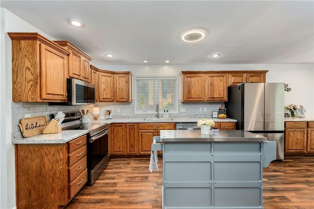 kitchen with stainless steel appliances, a sink, dark wood finished floors, brown cabinets, and recessed lighting