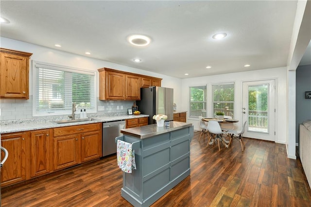 kitchen featuring a sink, appliances with stainless steel finishes, dark wood finished floors, brown cabinets, and a kitchen island