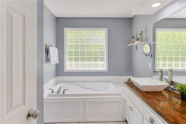 bathroom featuring plenty of natural light, a garden tub, and vanity