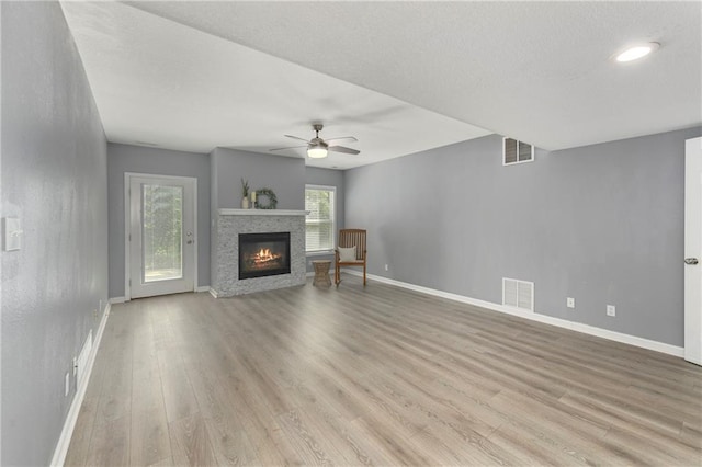 unfurnished living room with baseboards, light wood-style floors, a ceiling fan, and a glass covered fireplace