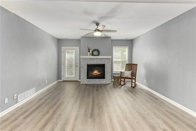 living room with wood finished floors, ceiling fan, a glass covered fireplace, and baseboards