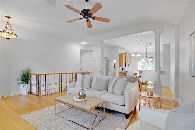 living area with ornate columns, a ceiling fan, light wood-type flooring, baseboards, and recessed lighting