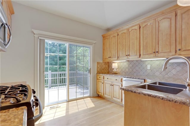kitchen featuring light brown cabinetry, gas stove, a sink, light wood-style flooring, and decorative backsplash