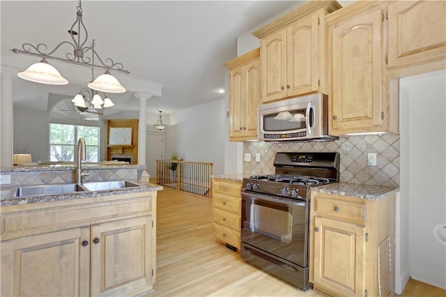 kitchen featuring black range with gas cooktop, stainless steel microwave, a sink, light brown cabinetry, and decorative backsplash