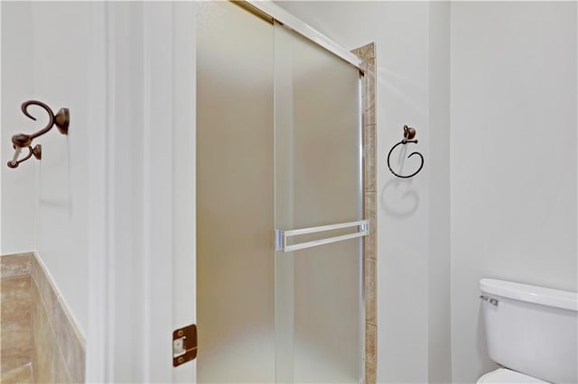 full bath featuring a stall shower and toilet