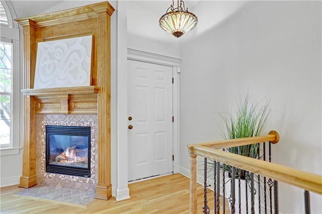 foyer entrance featuring wood finished floors, healthy amount of natural light, a tiled fireplace, and baseboards