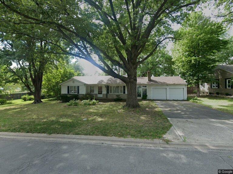 ranch-style house featuring an attached garage, concrete driveway, a front yard, and a chimney