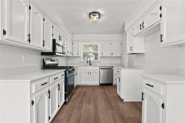 13300 Palmer Ave, Grandview, MO 64030 - kitchen featuring appliances with stainless steel finishes, dark wood-style flooring, white cabinetry, and light countertops
