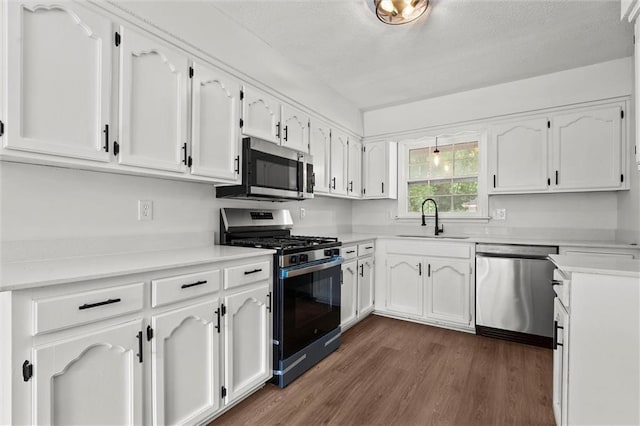 13300 Palmer Ave, Grandview, MO 64030 - kitchen featuring appliances with stainless steel finishes, dark wood-style flooring, white cabinetry, and light countertops