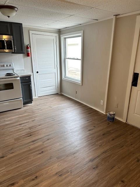 kitchen featuring white range with electric stovetop, stainless steel microwave, light wood-style flooring, light countertops, and baseboards