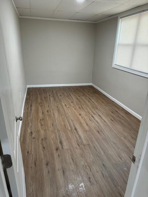 spare room featuring baseboards, wood finished floors, and a paneled ceiling