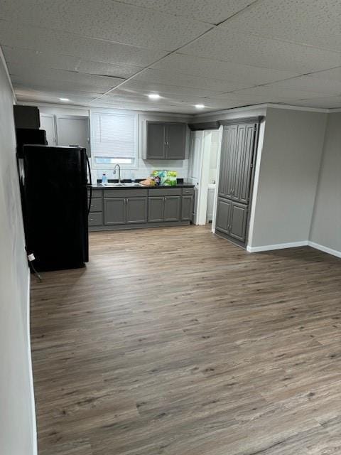 bar area featuring a sink, freestanding refrigerator, wood finished floors, baseboards, and ornamental molding