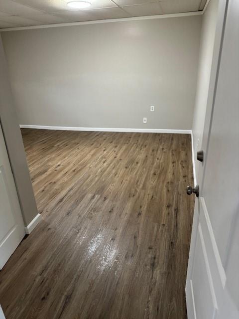 spare room featuring baseboards, wood finished floors, and ornamental molding