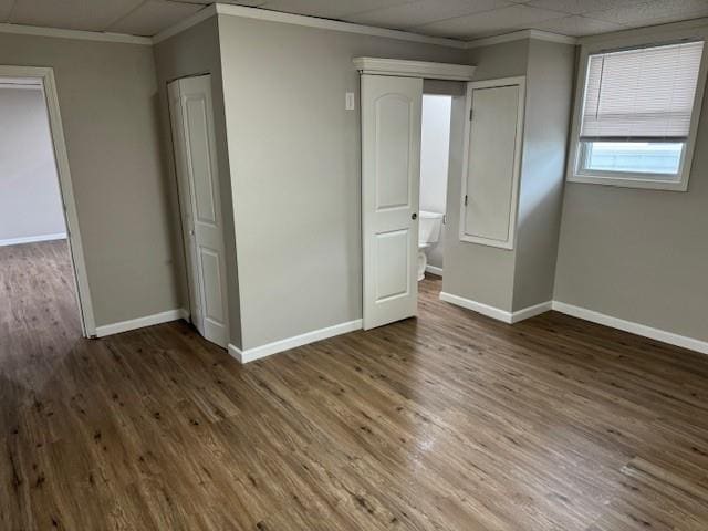 spare room featuring crown molding, baseboards, and wood finished floors