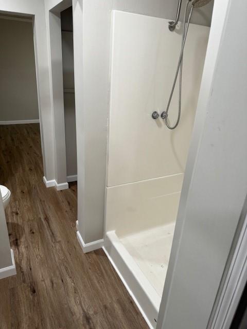 full bathroom featuring a shower stall, wood finished floors, and baseboards