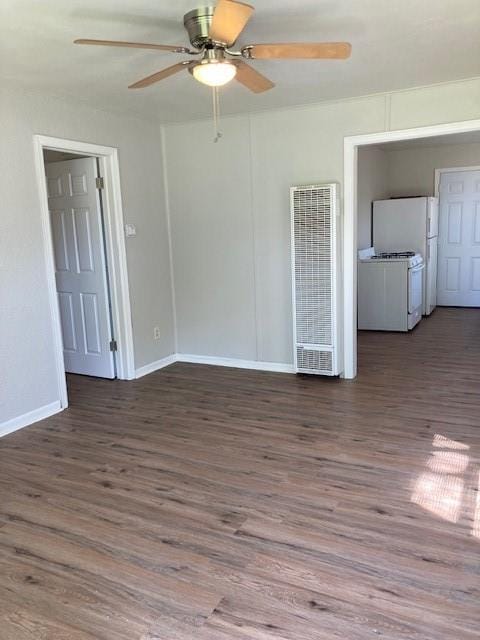 spare room featuring a heating unit, a ceiling fan, wood finished floors, and baseboards