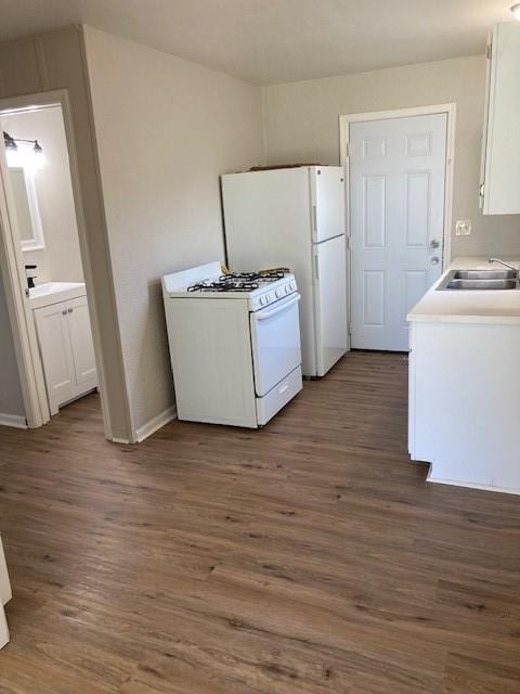 laundry area with a sink, dark wood-style flooring, and baseboards