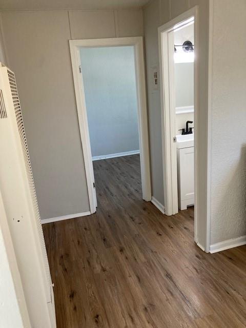 corridor with wood finished floors and baseboards
