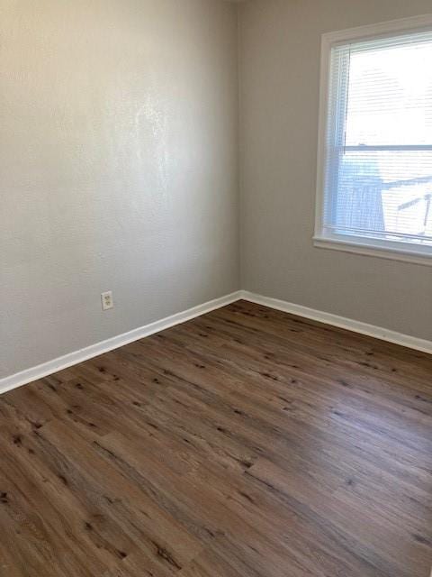 spare room featuring dark wood-type flooring and baseboards