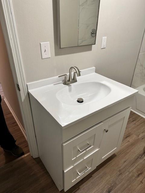 bathroom with wood finished floors, vanity, and a tub to relax in