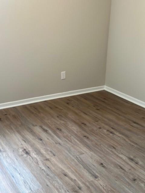 spare room with dark wood finished floors and baseboards