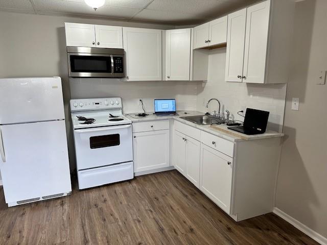 kitchen featuring white appliances, dark wood-type flooring, white cabinetry, and light countertops