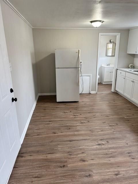 unfurnished dining area with wood finished floors, crown molding, a sink, and baseboards