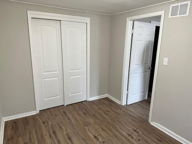 unfurnished bedroom featuring baseboards, dark wood finished floors, and a closet