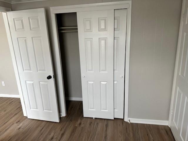unfurnished bedroom featuring baseboards, dark wood-type flooring, and a closet