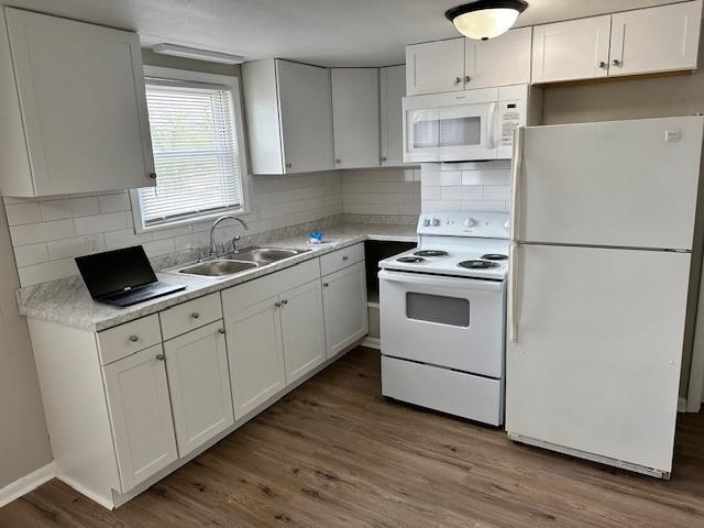 kitchen featuring white appliances, a sink, white cabinetry, wood finished floors, and light countertops