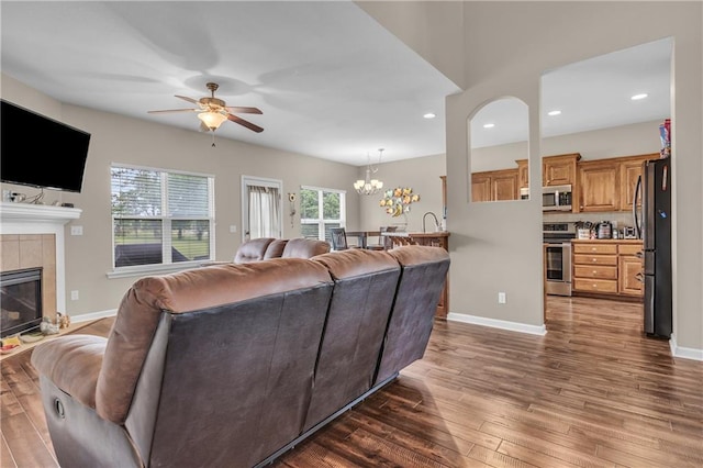 21923 W 116th Pl, Olathe, KS 66061 - living room featuring a ceiling fan, dark wood-type flooring, a tiled fireplace, a chandelier, and recessed lighting